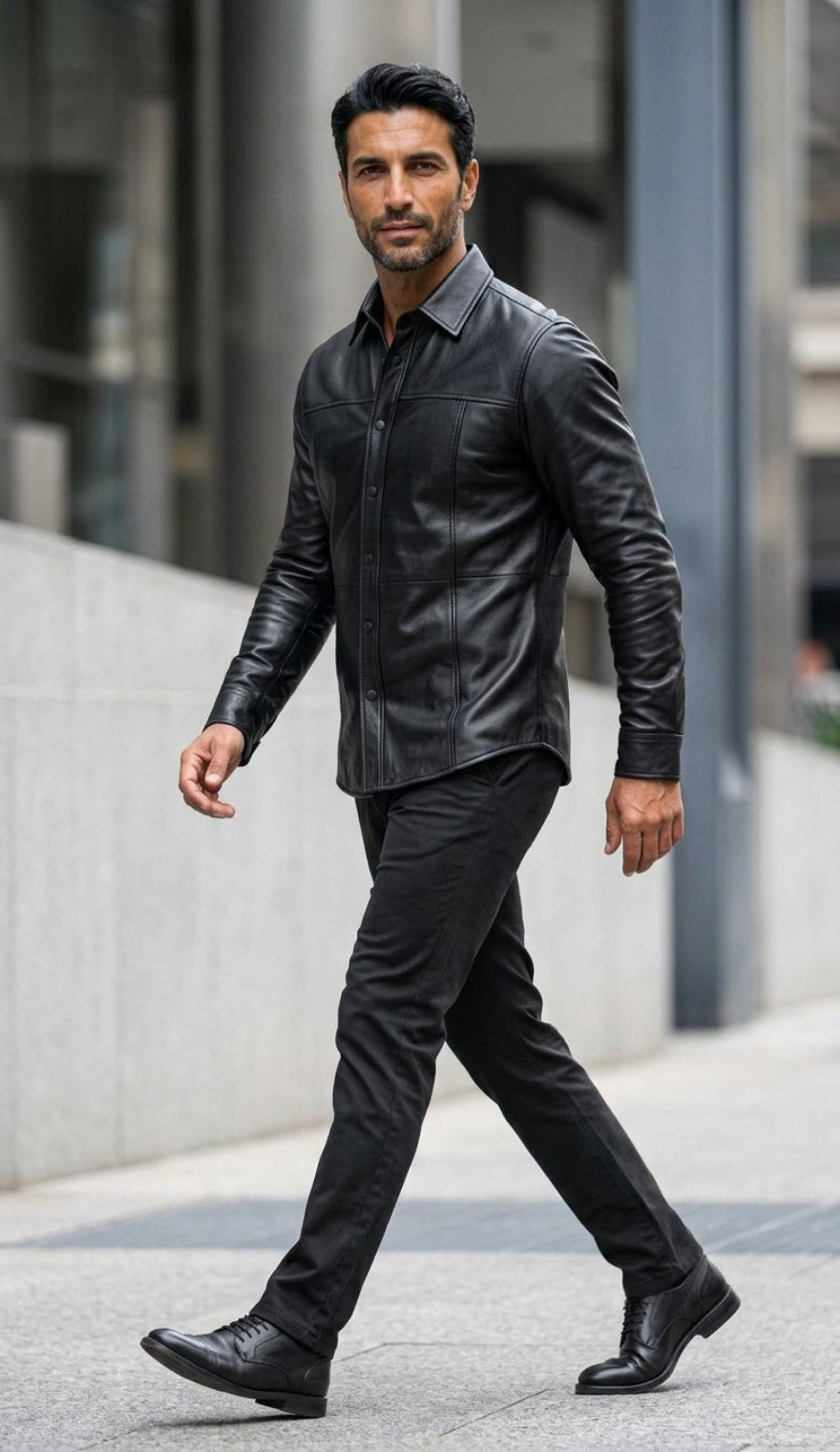 A man walking outdoors in our Black Custom Leather Shirt for Men, black trousers, and black leather shoes on a city sidewalk.