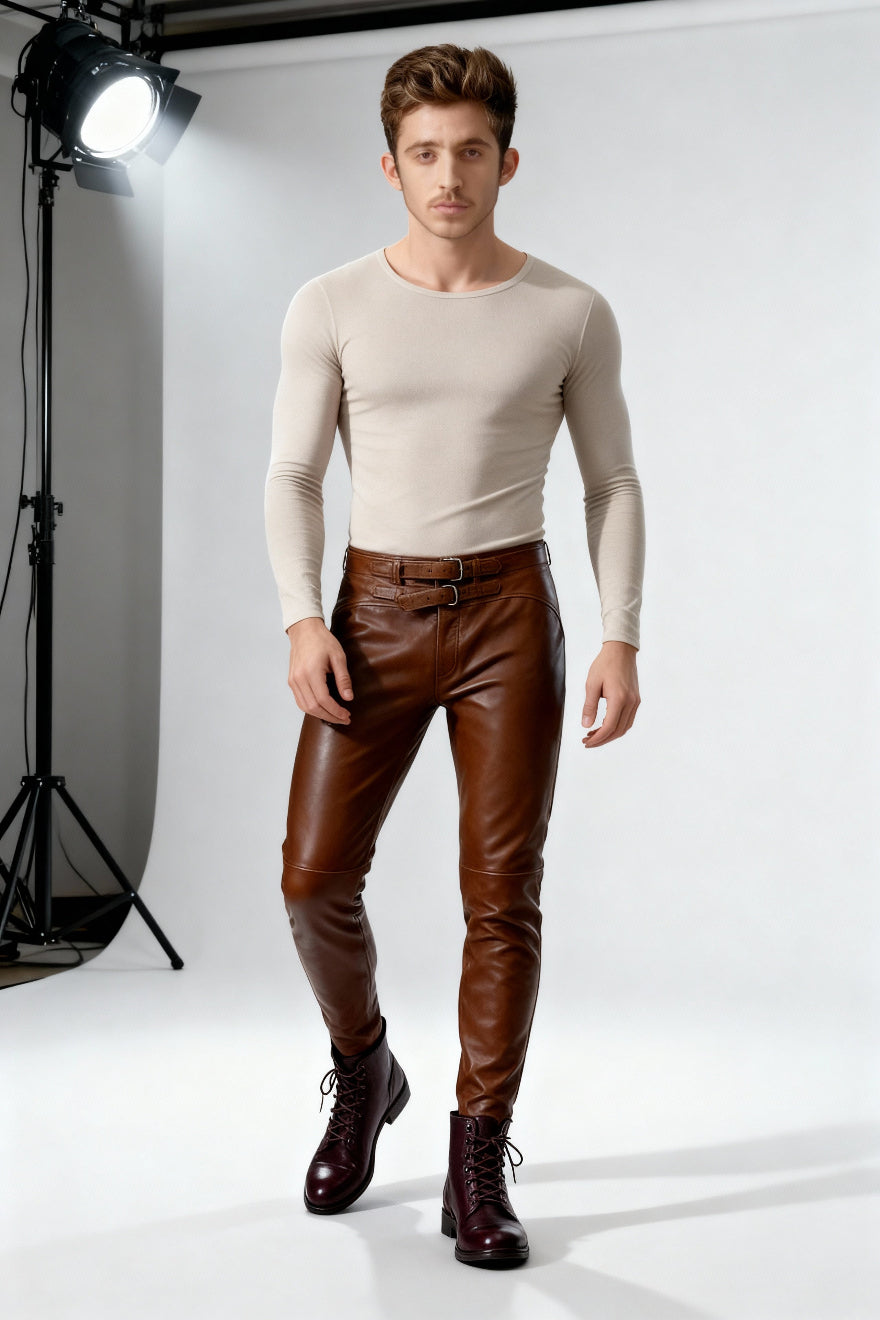 Man wearing a beige long-sleeve shirt and Dark Brown Leather Pants  standing in front of a white backdrop with studio lighting.