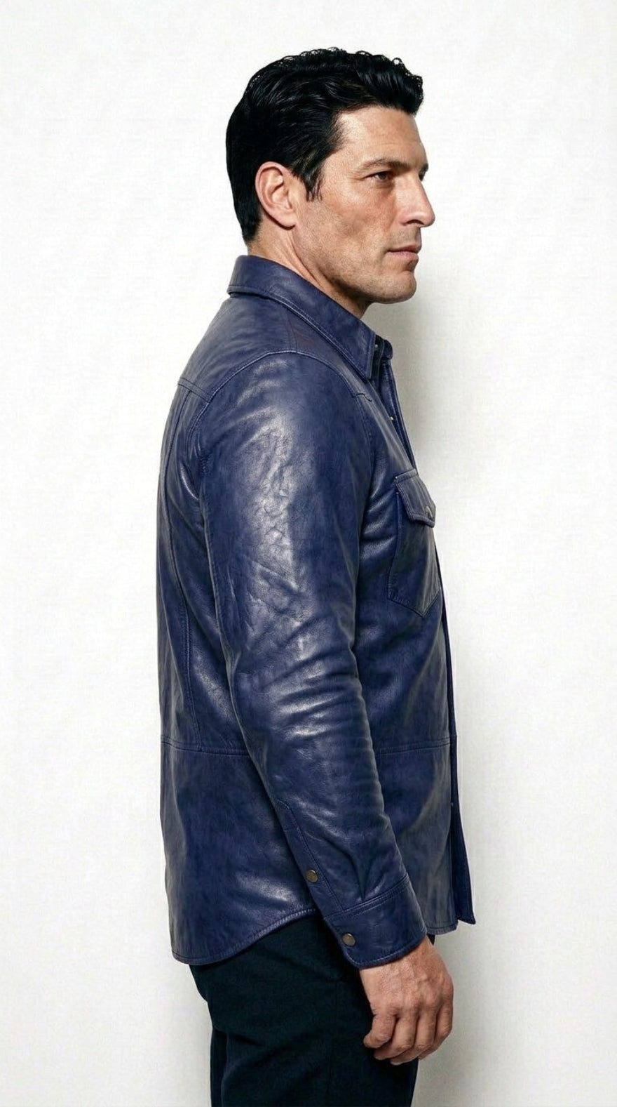 A man shown in profile wearing our  blue leather shirt against a plain light background.