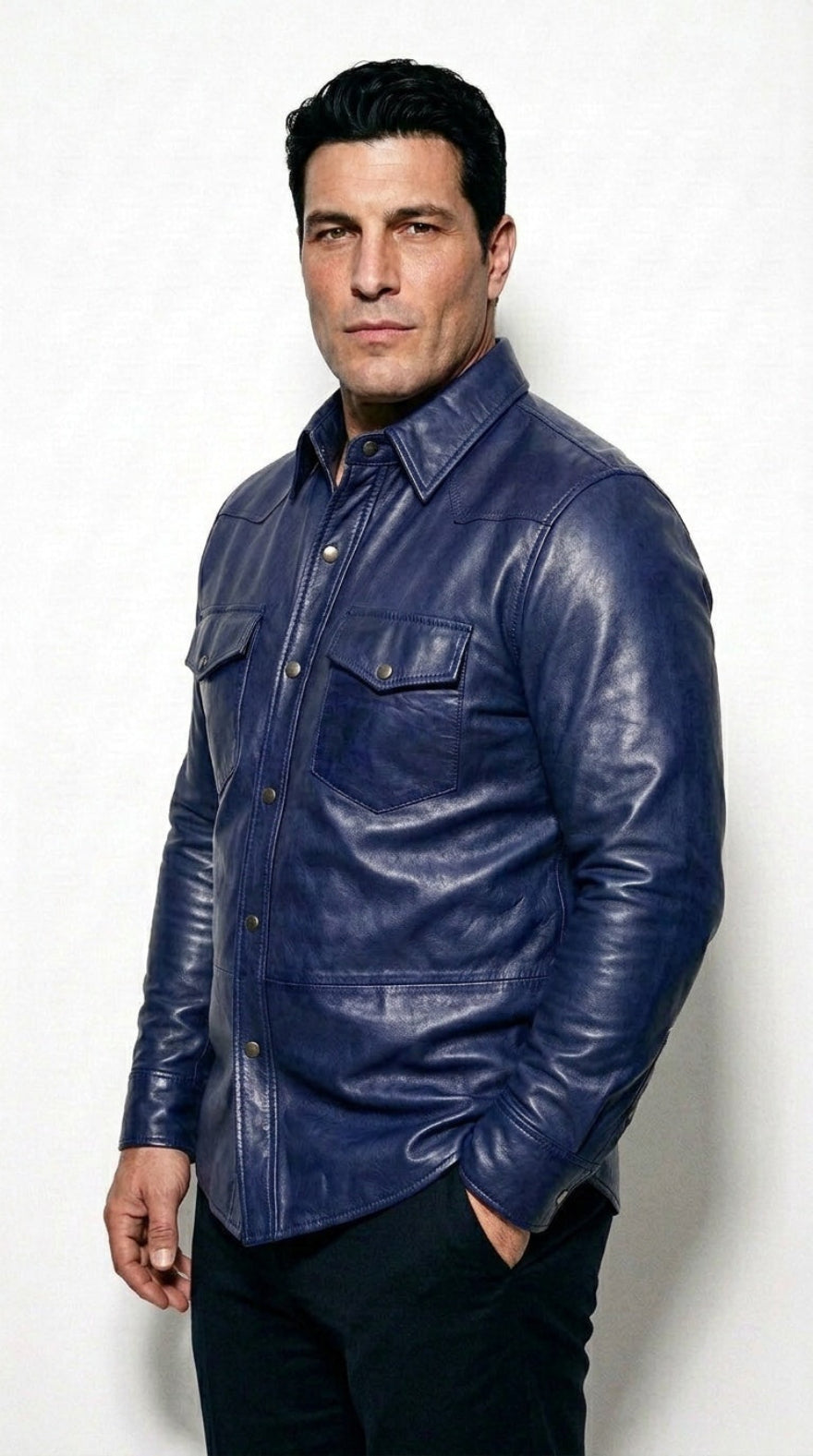A man wearing our blue leather button-up shirt and dark pants, standing against a light gray studio background.