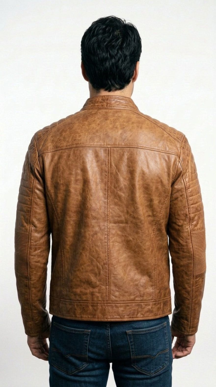 A man viewed from behind wearing a tan cafe racer leather jacket and dark blue jeans against a plain white background.