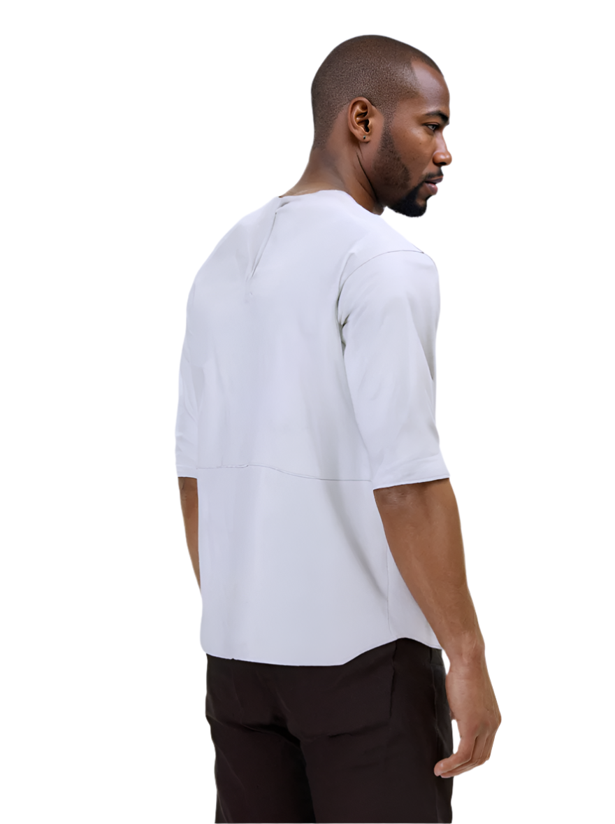Man wearing a white short-sleeve leatyher tee shirt and dark pants against a white background, back view.